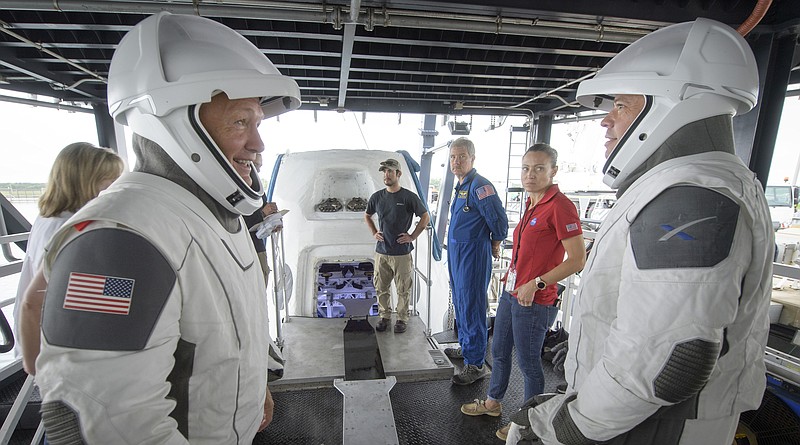 FILE - In this Aug. 13, 2019 file photo, NASA astronauts Doug Hurley, left, and Bob Behnken work with teams from NASA and SpaceX to rehearse crew extraction from SpaceX's Crew Dragon, which will be used to carry humans to the International Space Station, at the Trident Basin in Cape Canaveral, Fla. For the first time in nearly a decade, astronauts are about to blast into orbit aboard an American rocket from American soil. And for the first time in the history of human spaceflight, a private company -- SpaceX -- is providing the ride. (Bill Ingalls/NASA)
