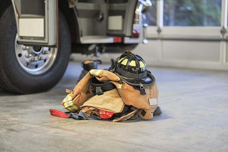 Fire bunker turnout-gear with a helmet is strategically set next to a fire engine in the fire station truck bay ready for a call. firefighter tile fire tile / Getty Images
