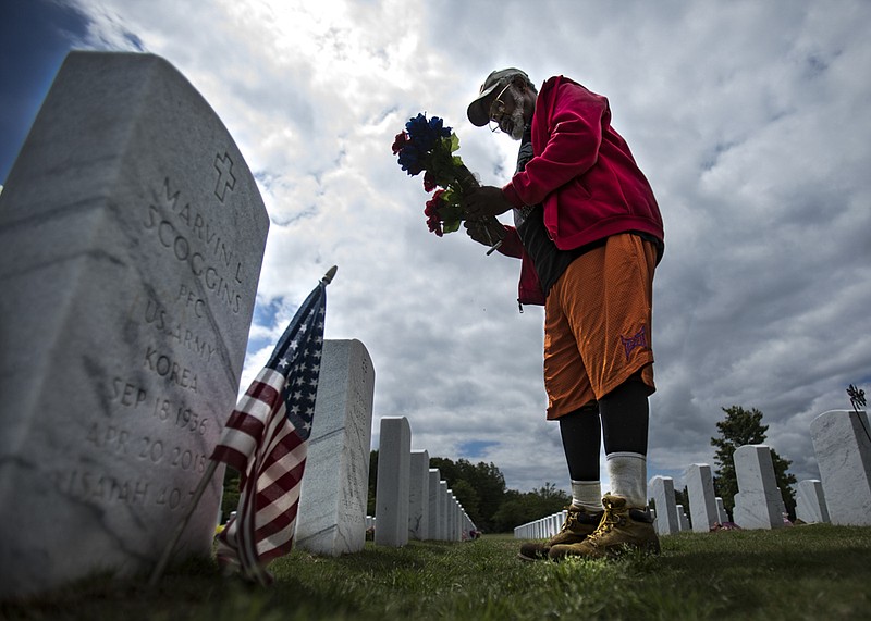 Staff photo by Troy Stolt / 72-year-old Vietnam war Veteran Henry Slayton places flowers at the grave of a deceased member of the American Veteran's Post 36 at the National Cemetery on Tuesday, May 19, 2020 in Chattanooga, Tenn. For the last seven years Slayton has honored his fellow veterans who have passed away before Veterans and Memorial Day, he plans to continue to do so for as long as he can.