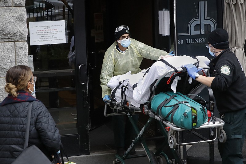FILE- In this April 17, 2020, file photo, a patient is wheeled into Cobble Hill Health Center by emergency medical workers in the Brooklyn borough of New York. On Thursday, April 23, 2020, New York Gov. Andrew Cuomo said that nursing homes in New York must immediately report how they have complied with regulations for resident care during the coronavirus, and non-compliant facilities could face hefty fines or lose their licenses. (AP Photo/John Minchillo, File)