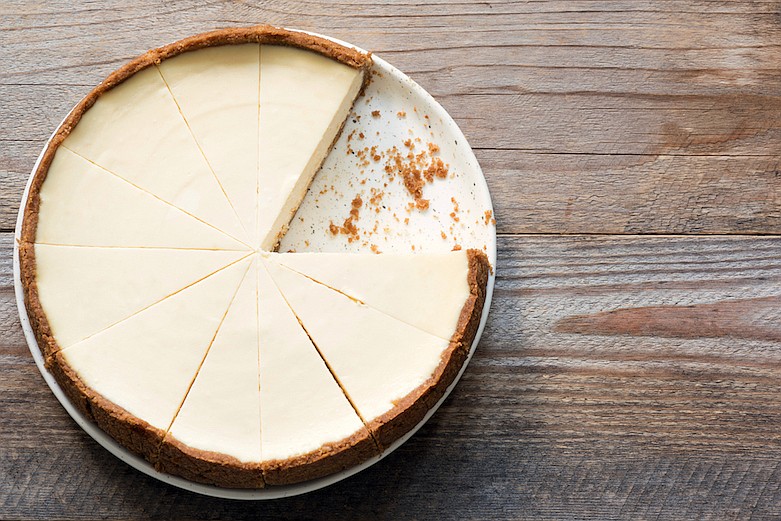 Cheesecake sliced on rustic wood. / Getty Images/iStock/Arx0nt