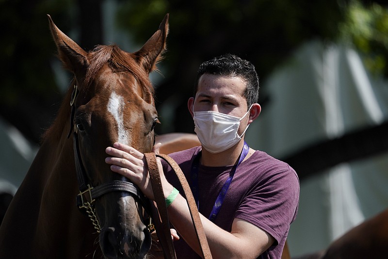 AP photo by Ashley Landis / A groom wearing a face mask leads a horse to the track Friday at Santa Anita Park in Arcadia, Calif. Horse racing returned to the track after being idled for a month and a half because of public health officials' concerns about the coronavirus pandemic.