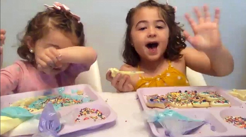 In this May 23, 2020, image from video, Liyana Mujovic, 2, her sister Suhaila, 5, and a group of friends decorate cookies for Eid al-Fitr over Zoom as they celebrate the end of a month-long fast, marking the end of Ramadan. (Courtesy of Hoda Rifai Bashjawish via AP)