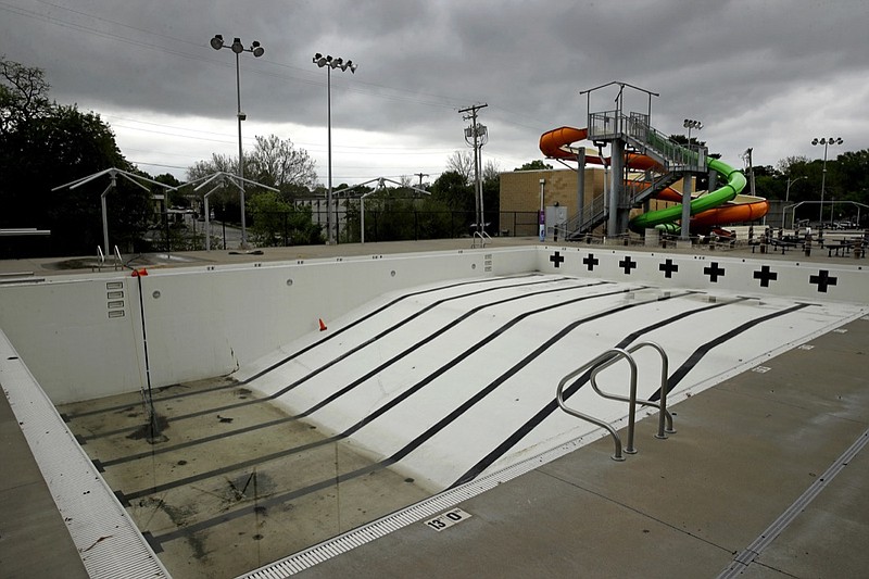 In this photo taken Friday, May 15, 2020, the public pool in Mission, Kan. is lifeless as plans remain in place to keep the pool closed for the summer to help prevent the spread of COVID-19. As warm weather approaches and many public pools remain closed there has been a surge of people using backyard pools as well at taking to water activities on lakes and rivers to get out and cool off. (AP Photo/Charlie Riedel)