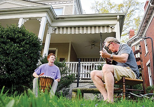 Ned O'Neil plays the bongos while father Steve plays the guitar. Residents of the Fort Wood Historic District took to their porches and yards to share their talents as a way to ward off the tension of the coronavirus pandemic. / Staff Photo by Robin Rudd