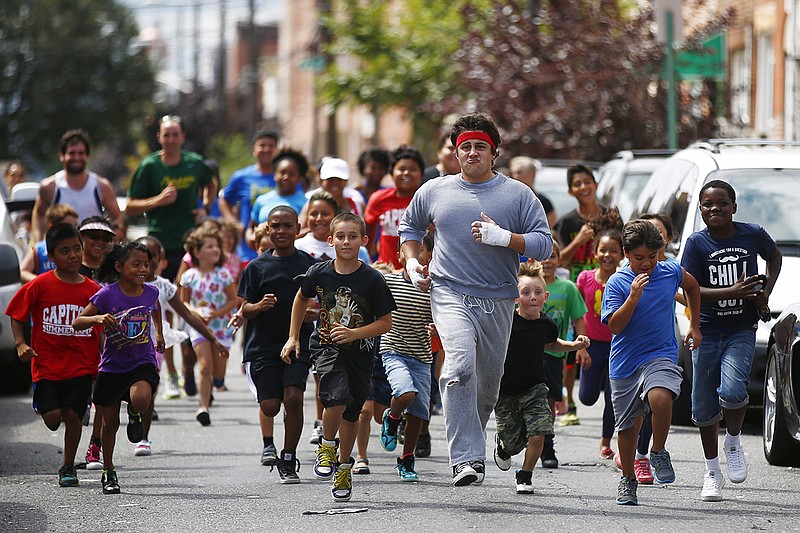 AP photo by Matt Rourke / Rocky impersonator and tour guide Mike Kunda leads a group of children as they run to Pat's King of Steaks on Aug. 13, 2014, in Philadelphia.