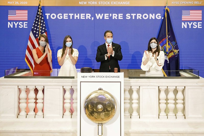 In this image provided by the New York Stock Exchange, New York State Gov. Andrew Cuomo, center, applauds as he rings the opening bell of the New York Stock Exchange with with New York Stock Exchange President Stacey Cunningham, right, Tuesday, May 26, 2020 in New York. The NYSE allowed a limited number of traders back to the floor with social distancing guidelines and face masks. (Courtney Crow/New York Stock Exchange via AP)