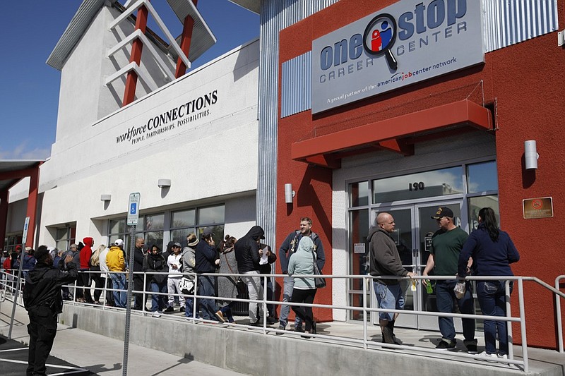 FILE - In this March 17, 2020, file photo, people wait in line for help with unemployment benefits at the One-Stop Career Center in Las Vegas. The coronavirus pandemic has been particularly brutal to the tourism-dependent economies of Nevada and Hawaii, lifting the unemployment rate in both states to about one-quarter of the workforce. (AP Photo/John Locher, File)