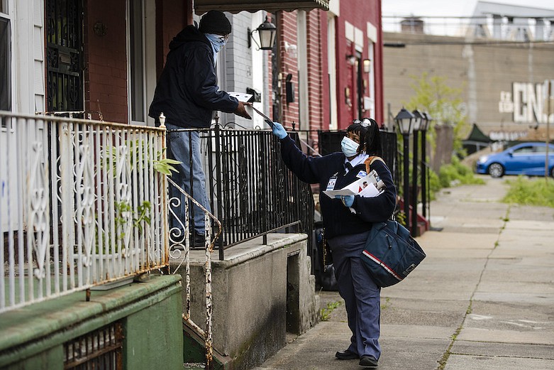 United States Postal Service carrier Henrietta Dixon delivers mail to Alvin Fields in Philadelphia, Wednesday, May 6, 2020. Fields called Dixon "absolutely wonderful." (AP Photo/Matt Rourke)