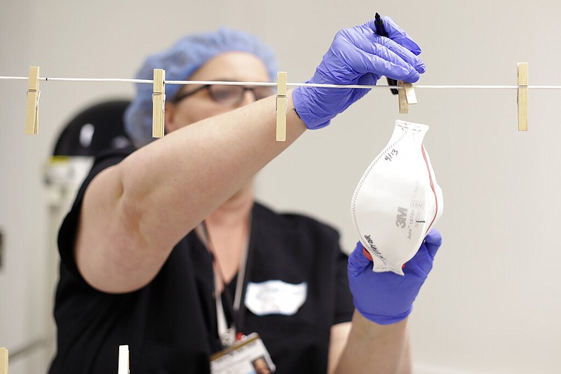 In this April 21, 2020 photo, Robin Adkins, a nurse and senior director of Clinical Engagement at Vanderbilt University Medical Center, removes masks used during the COVID-19 pandemic after they were sanitized with ultraviolet light at the medical center in Nashville, Tenn. (AP Photo/Mark Humphrey)