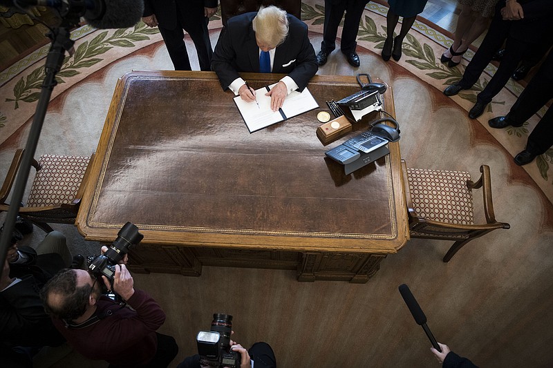 President Donald Trump signs an executive order in the Oval Office of the White House in January 2017. Trump moved immediately after his inauguration to dismantle environmental regulations as he signed a document clearing the way to government approval of the Keystone XL pipeline. Trump is losing many of those bids now to federal court rulings. / Photo by Doug Mills, The New York Times