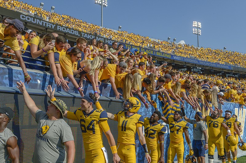 AP photo by Craig Hudson / University of West Virginia football players high-five fans after the Mountaineers beat Kansas 38-22 on Oct. 6, 2018, in Morgantown, W. Va.