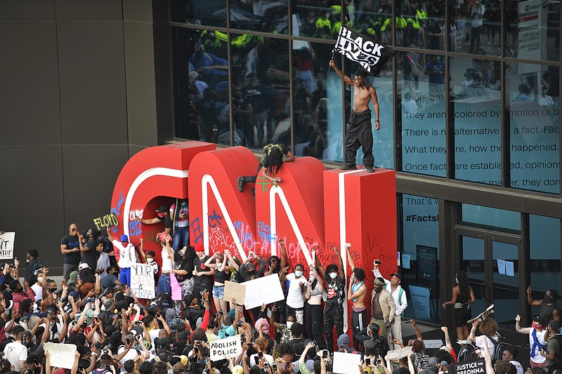 Demonstrators paint on the CNN logo during a protest, Friday, May 29, 2020, in Atlanta, in response to the death of George Floyd in police custody on Memorial Day in Minneapolis. The protest started peacefully earlier in the day before demonstrators clashed with police. (AP Photo/Mike Stewart)