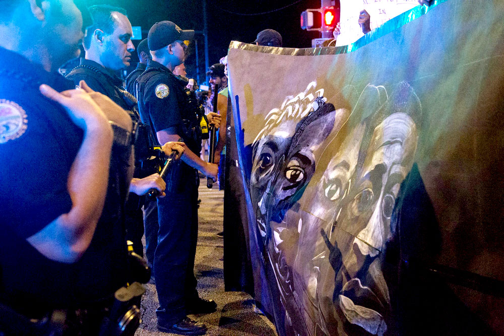 Staff photo by Troy Stolt / Chattanooga police line up at the corner of Frazier Avenue and Tremont Street, Saturday night, as a crowd blocks their view with a large banner during protests over the murder of George Floyd by Minneapolis police officers.