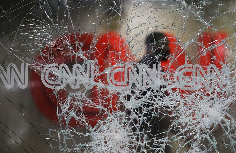 A security guard walks behind shattered glass at the CNN building at the CNN Center in the aftermath of a demonstration against police violence on Saturday, May 30, 2020, in Atlanta. (AP Photo/Brynn Anderson)