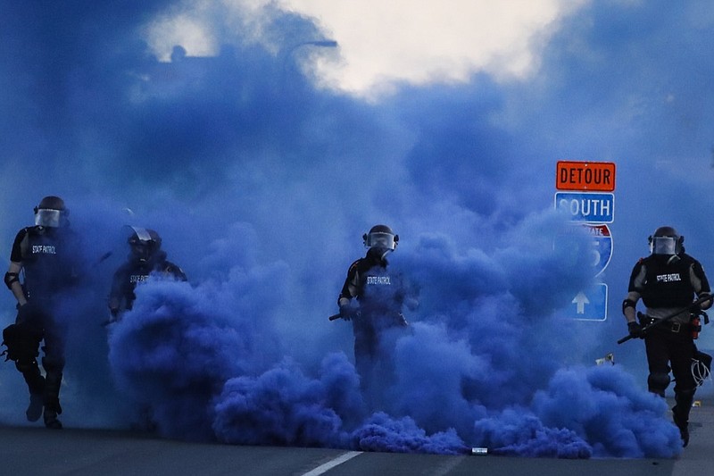 Police in riot gear walk through a cloud of blue smoke as they advance on protesters near the Minneapolis 5th Precinct, Saturday, May 30, 2020, in Minneapolis. Protests continued following the death of George Floyd, who died after being restrained by Minneapolis police officers on Memorial Day. (AP Photo/John Minchillo)