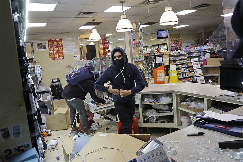 Photo by Seth Wenig of The Associated Press / People look through a 7-Eleven store after they entered through a smashed window in New York on Sunday, May 31, 2020. Demonstrators took to the streets of New York to protest the death of George Floyd, who died May 25 after he was pinned at the neck by a Minneapolis police officer.