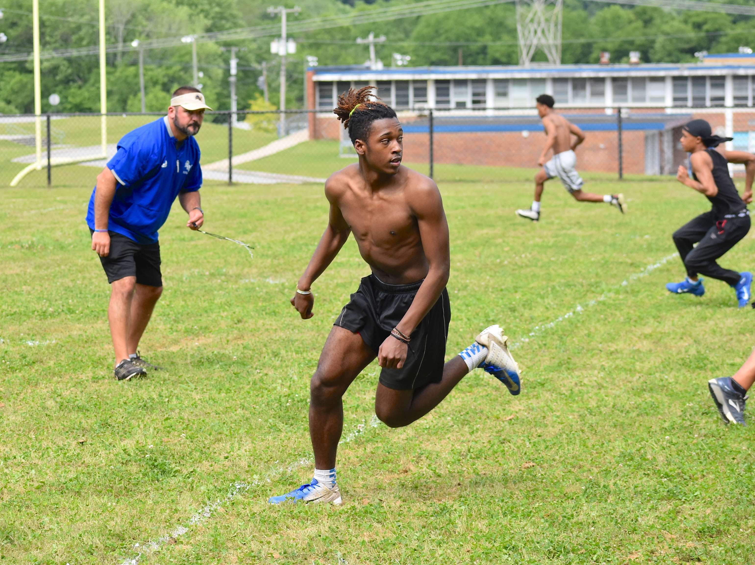 Staff photo by Patrick MacCoon / Red Bank High School's OJ Jackson runs a route as coach Chris Brown looks on during a training session Monday. Hamilton County schools resumed football activities for the first time since mid-March, when sports shut down due to the coronavirus pandemic.