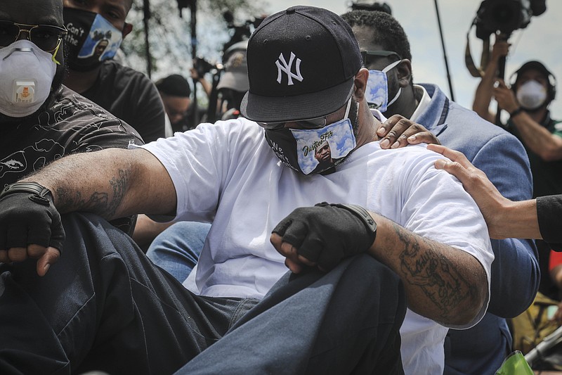 An emotional Terrence Floyd is comforted as he sits at the spot at the intersection of 38th Street and Chicago Avenue, Minneapolis, Minn., where his brother George Floyd, encountered police and died while in their custody, Monday, June 1, 2020. (AP Photo/Bebeto Matthews)

