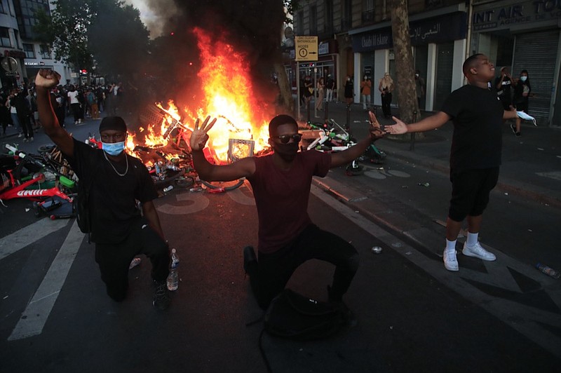 Protesters kneel and react by a burning barricade during a demonstration Tuesday, June 2, 2020 in Paris. Paris riot officers fired tear gas as scattered protesters threw projectiles and set fires at an unauthorized demonstration against police violence and racial injustice. Several thousand people rallied peacefully for two hours around the main Paris courthouse in homage to George Floyd and to Adama Traore, a French black man who died in police custody. (AP Photo/Michel Euler)

