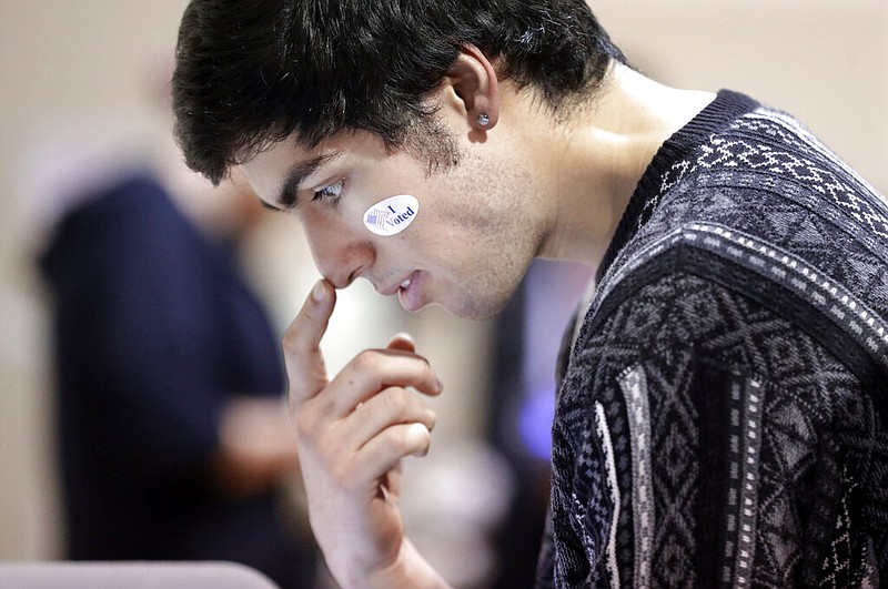 David Flores-Figueroa wears his voting sticker on his face as he reads over the ballot before voting on Super Tuesday at the Cleveland Park Community Center precinct, Tuesday, March 3, 2020, in Nashville, Tenn. (AP Photo/Mark Humphrey)