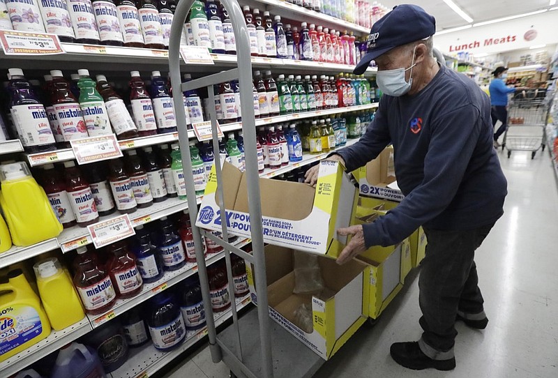 In this Wednesday, June 3, 2020 photo, Juan Santos stocks shelves at the Presidente Supermarket in the Little Havana neighborhood of Miami. The U.S. government is set to issue its latest report on the layoffs that have left millions unemployed but have steadily slowed as many businesses have begun to reopen and to rehire some laid-off workers. (AP Photo/Wilfredo Lee)