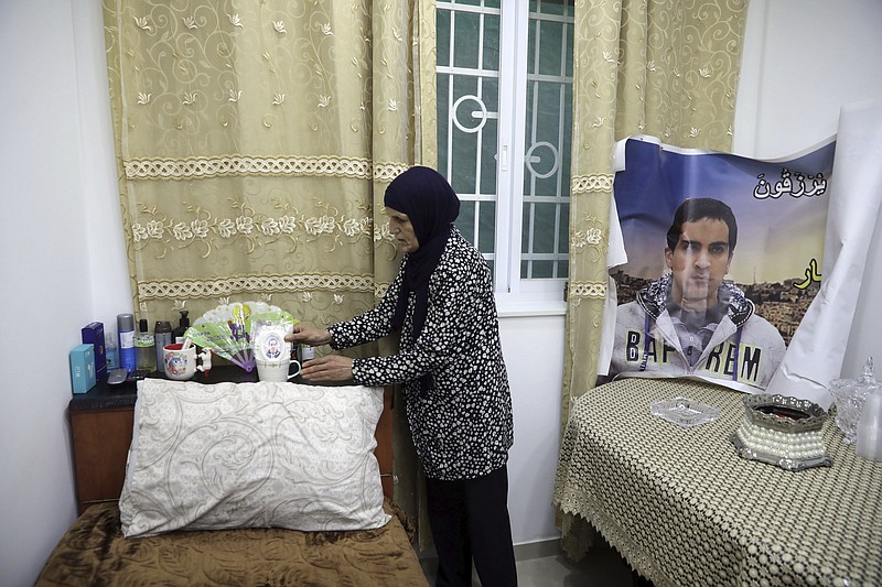 In this Wednesday, June 3, 2020 photo, Rana, mother of Eyad Hallaq, arranges his room in their home in East Jerusalem's Wadi Joz. Early Saturday, Hallaq, a 32-year-old Palestinian with severe autism, was chased by Israeli border police forces into a nook in Jerusalem's Old City and fatally shot as he cowered next to a garbage bin after apparently being mistaken as an attacker. He was just a few meters from his beloved Elwyn El Quds school. (AP Photo/Mahmoud Illean)

