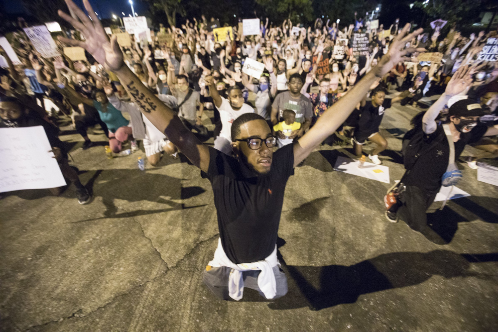 Staff photo by Troy Stolt / Protester Lebron Nash holds his hands up while kneeling in College Hill Courts during a peaceful demonstration on the sixth day of protests over the death of George Floyd on Thursday, June 4, 2020 in Chattanooga, Tenn.