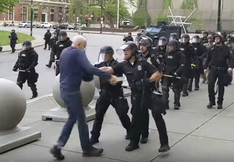 In this image from video provided by WBFO, a Buffalo police officer appears to shove a man who walked up to police Thursday, June 4, 2020, in Buffalo, N.Y. Video from WBFO shows the man appearing to hit his head on the pavement, with blood leaking out as officers walk past to clear Niagara Square. Buffalo police initially said in a statement that a person "was injured when he tripped & fell," WIVB-TV reported, but Capt. Jeff Rinaldo later told the TV station that an internal affairs investigation was opened. Police Commissioner Byron Lockwood suspended two officers late Thursday, the mayor's statement said. (Mike Desmond/WBFO via AP)