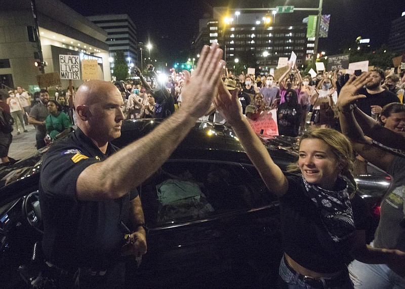 Staff photo by Troy Stolt / A Chattanooga police officer high fives a protester during protests over police brutality after George Floyd was killed by Minneapolis police on Friday, June 5, 2020 in Chattanooga, Tenn.