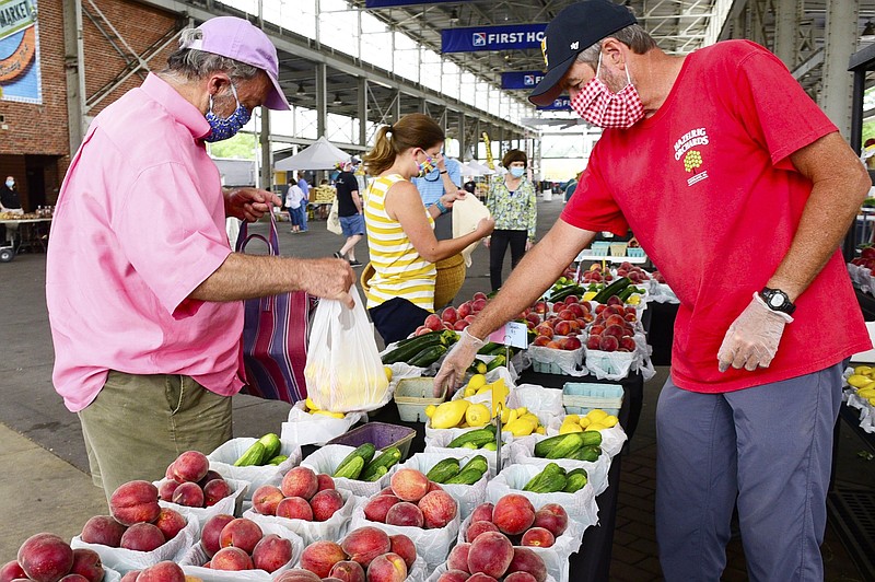 Staff Photo by Robin Rudd / Mike Hazelrig, right, with Hazelrig's Peaches of Cleveland Alabama, waits on Keny Hays. The Chattanooga Market returned recently. Vendors are required to wear masks, and customers are asked to do so.