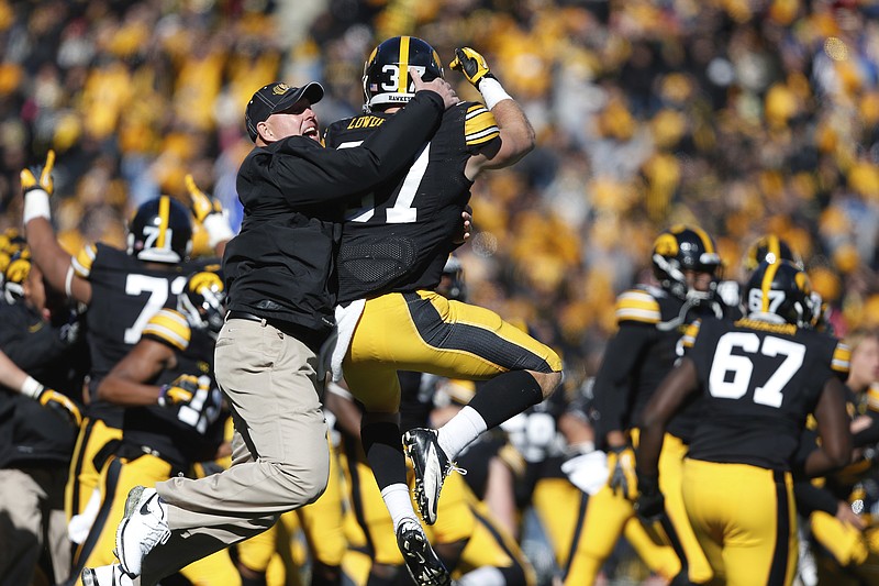 AP photo by Brian Ray / Iowa strength and conditioning coach Chris Doyle, front left, celebrates with defensive back John Lowdermilk after the Hawkeyes' overtime win against Northwestern on Oct. 26, 2013, in Iowa City.