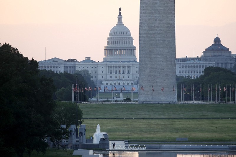 With the U.S. Capitol and Washington Monument in the distance, a man stands at the edge of the Lincoln Memorial Reflecting Pool at sunrise, Sunday, June 7, 2020, in Washington, the morning after massive protests over the death of George Floyd, who died after being restrained by Minneapolis police officers. (AP Photo/Patrick Semansky)