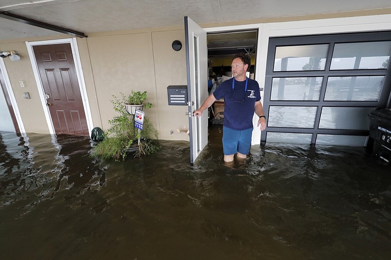 Rudy Horvath walks out of his home, a boathouse in the West End section of New Orleans, as it takes on water a from storm surge in Lake Pontchartrain in advance of Tropical Storm Cristobal, Sunday, June 7, 2020. (AP Photo/Gerald Herbert)