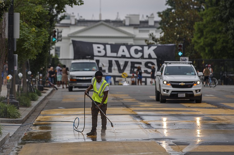 A city worker cleans the words Black Lives Matter painted in bright yellow letters on 16th Street at the site of protests, Wednesday, June 10, 2020, near the White House in Washington. The protests began over the death of George Floyd, a black man who was in police custody in Minneapolis. Floyd died after being restrained by Minneapolis police officers. (AP Photo/Carolyn Kaster)