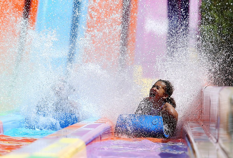 Staff file photo / Amiraqle Lee slides down the Winnie 500 ahead of her sister Gloria Nunez, who is barely visible through a splash of water on the left, at Lake Winnepesaukah's SoakYa water park last September. The park's opening this summer has been delayed by the novel coronavirus.