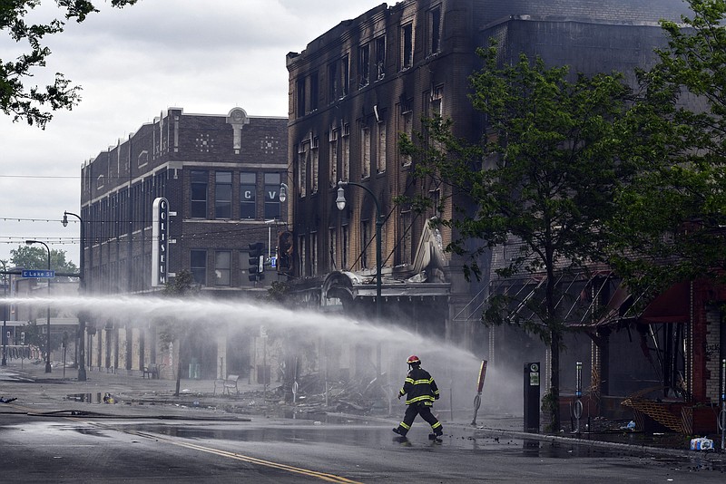 Photo by Dave Schwarz of The St. Cloud Press via The Associated Press / A firefighter walks past smoldering buildings on Friday, May 29, 2020, after people rioting to protest the death of George Floyd lit fires on Thursday night near the intersection of Lake Street and Minnehaha Avenues in Minneapolis. Protests over the death of Floyd in Minneapolis police custody have spread to other areas across the United States.
