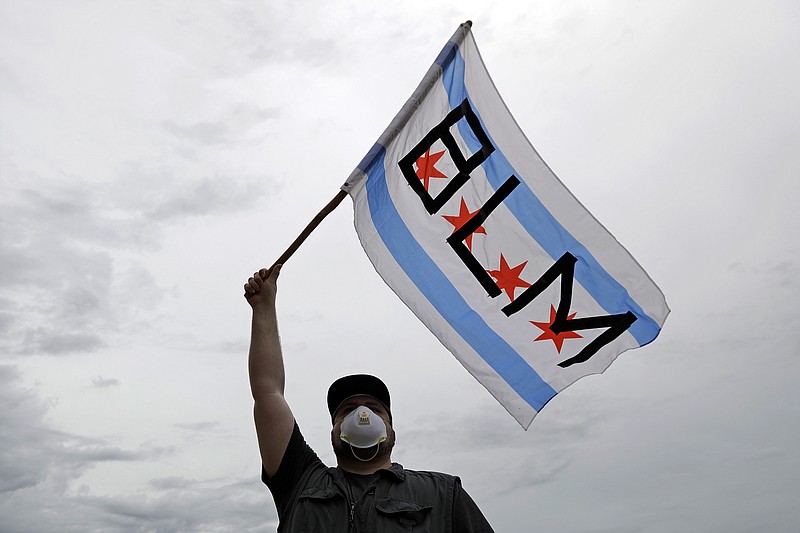 FILE - In this June 3, 2020, file photo, a protester waves a city of Chicago flag emblazoned with the acronym BLM for Black Lives Matter, outside the Batavia, Ill., City Hall during a protest over the death of George Floyd. Black Lives Matter has gone mainstream — and black activists are carefully assessing how they should respond. (AP Photo/Nam Y. Huh, File)


