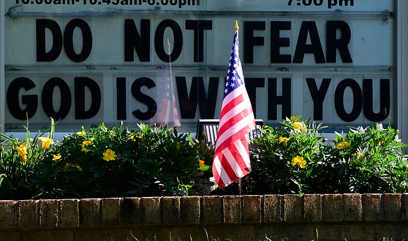Staff Photo by Robin Rudd / A flag is placed in a planter in front of the sign for the Midway Baptist Church in Indian Springs, along Highway 41 in Georgia.