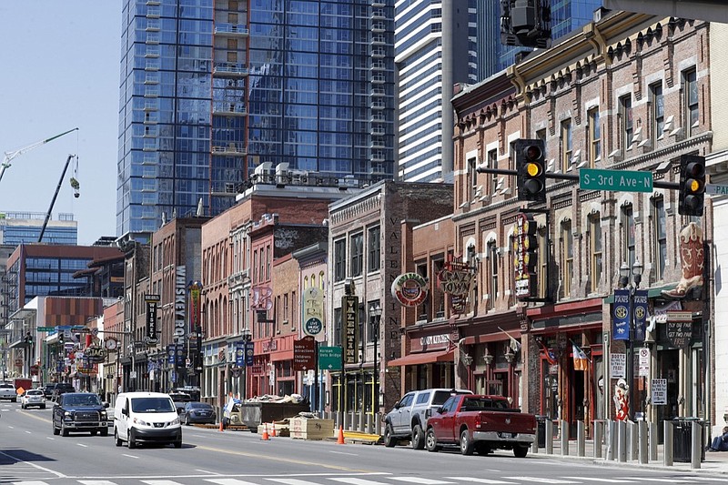 This April 16, 2020, photo shows restaurants, bars and stores on Broadway in Nashville, Tenn. (AP Photo/Mark Humphrey)