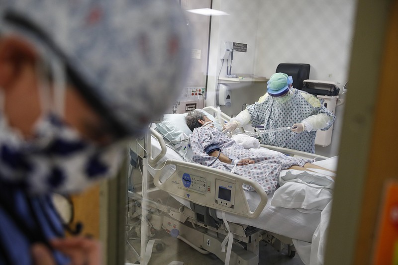 FILE - In this April 20, 2020, file photo, resident physician Leslie Bottrell stands outside a room at an Intensive Care Unit as a nurse suctions the lungs of a COVID-19 patient at St. Joseph's Hospital in Yonkers, N.Y. A U.S. government report says death rates are 12 times higher for coronavirus patients with chronic illnesses than for others who become infected. The Centers for Disease Control and Prevention report Monday, June 15 highlights the dangers posed by these conditions. They include heart disease, diabetes and chronic lung ailments, such as asthma or emphysema. (AP Photo/John Minchillo, File)


