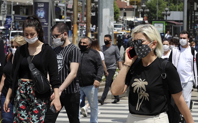 People wearing face masks to protect against the spread of coronavirus, walk in the main Kizilay Square, in Ankara, Turkey, Tuesday, June 16, 2020. Turkey has made the wearing of face masks mandatory in five more provinces, following an uptick in COVID-19 cases. Health Minister Fahrettin Koca tweeted early Tuesday that the wearing of masks is now compulsory in 42 of Turkey's 81 provinces.(AP Photo/Burhan Ozbilici)


