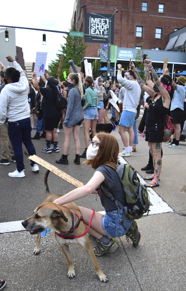 Staff Photo by Robin Rudd / A woman holds her dog as the march pauses at the intersection of Houston and Market Streets. Protesters gathered at Miller Park and marched south past some of Chattanooga's tourism icons in reaction to the killing of George Floyd and other police brutalities on June 17, 2020.