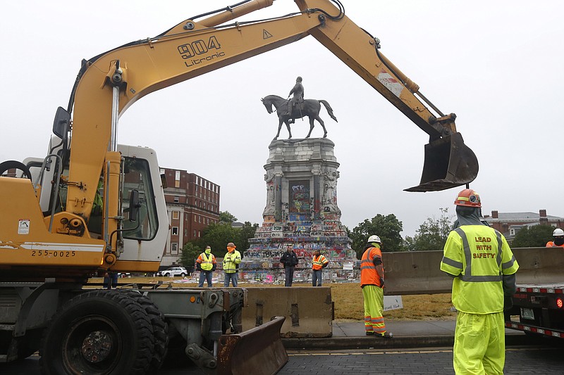Workers for The Virginia Department of General Services install concrete barriers around the statue of Confederate General Robert E. Lee on Monument Avenue Wednesday June 17, 2020, in Richmond, Va. The barriers are intended to protect the safety of demonstrators as well as the structure itself. (AP Photo/Steve Helber)