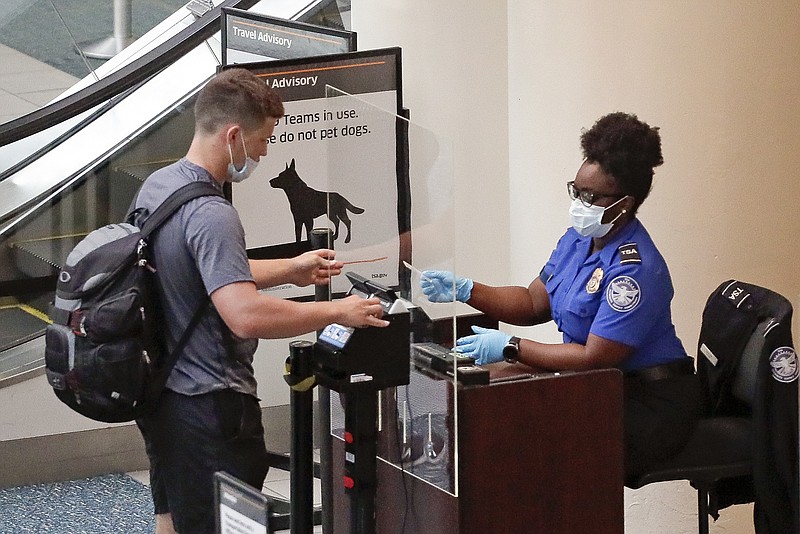 FILE - In this June 17, 2020 file photo, a TSA worker, right, checks a passenger before entering a security screening at Orlando International Airport in Orlando, Fla. A high-ranking Transportation Security Administration official says the agency is falling short when it comes to protecting airport screeners and the public from the new coronavirus, according to published reports. A federal office that handles whistleblower complaints has ordered an investigation. (AP Photo/John Raoux, File)


