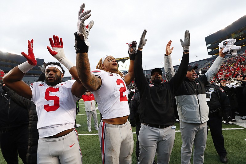 AP photo by Paul Sancya / From left, Ohio State football players Baron Browning and Chase Young, linebackers coach Al Washington and head coach Ryan Day celebrate the Buckeyes win at Michigan on Nov. 30, 2019.