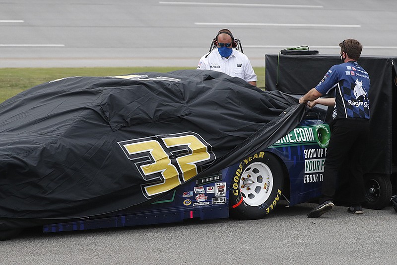 AP photo by John Bazemore / NASCAR driver Corey LaJoie's car is covered as inclement weather rolls in before the Cup Series race scheduled for Sunday at Talladega Superspeedway in Alabama.