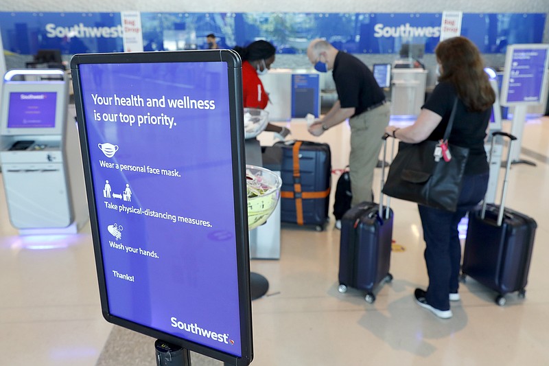 A sign reminds travelers to take safety measures against COVID-19 as they arrive for flights out of Love Field in Dallas, Wednesday, June 24, 2020. New York, Connecticut and New Jersey asked Wednesday for travelers from states with high coronavirus infection rates to go into quarantine for 14 days in a bid to preserve hard-fought gains as caseloads rise elsewhere in the country. (AP Photo/Tony Gutierrez)


