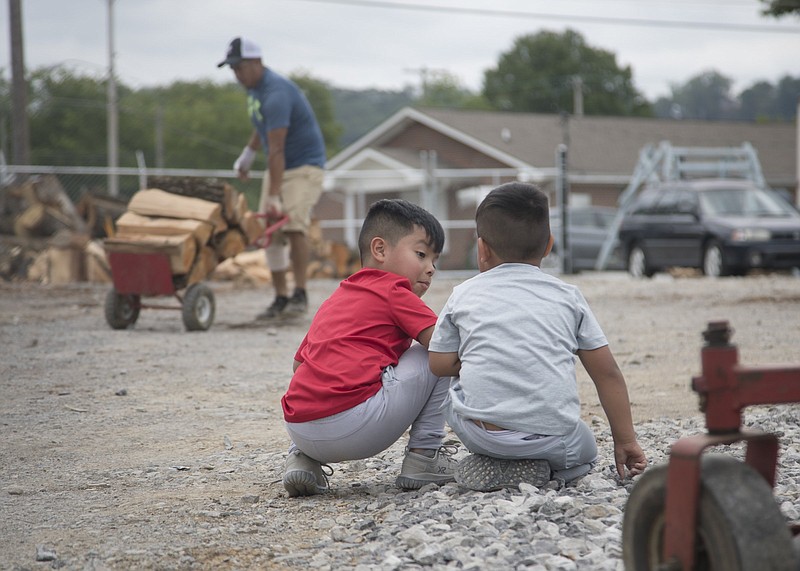 Staff photo by Troy Stolt / Brothers Romeo and Anthony Perez play as their father Gilber moves stacks of wood at Garcia Tree Service on 37th street on Thursday, May 14, 2020 in Chattanooga, Tenn. Their 37407 ZIP code has been hit disproportionately hard by COVID-19.