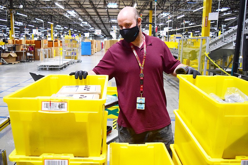 Staff Photo by Robin Rudd / Amazon Associate Casey Nash wears a mask as he works in the huge facility in Enterprise South.  Amazon has taken steps to combat the coronavirus and safeguard the health of the workers at their CHA1 fulfillment center.